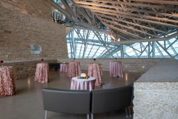 Une terrasse en pierre de Tyndall décorée pour une réception avec des nappes en satin rose pâle recouvrant des tables de cocktail et des canapés en cuir brun.