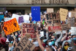 Un grand groupe de personnes tenant des pancartes avec des slogans en anglais qui disent, entre autres, « Les vies noires comptent », « Assez, c’est assez » et « Votre silence est une trahison ». 