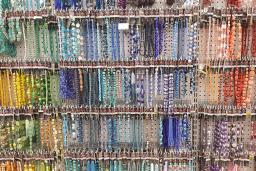 Des perles de couleurs vives, de formes et de tailles diverses sont suspendues à des crochets sur un tableau blanc.