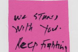 A piece of cloth with "We stand with you. Keep fighting!" written.