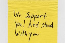 A piece of cloth with "We support you! And stand with you." written.