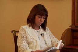 Une femme est assise en train de lire un livre. Il s’agit de Katerina Sakellaropoulou, présidente de la République hellénique.