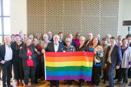  Vingt-huit membres du conseil d’ administration du Fonds Purge LGBT et du Comité consultatif du Monument national LGBTQ2+ posant ensemble et tenant un drapeau arc-en-ciel, lors de la première session de visualisation du Monument en 2019.