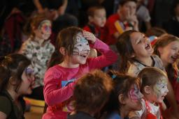 Un groupe d’enfants aux visages peints rient et font des gestes.