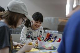 Des enfants d'âges différents sont assis autour d'une table en train de bricoler.