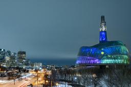 De nuit, les panneaux de verre du MCDP sont éclairés en bleu, vert et violet.