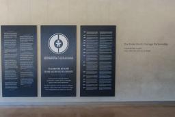 Grands panneaux bleu foncé avec texte et graphiques blancs exposés dans le Corridor communautaire du Musée canadien pour les droits de la personne. Le panneau central comporte un logo circulaire et commémore le 40e anniversaire du Centre canadien de protection de l'enfance. Les deux panneaux de chaque côté présentent du texte bilingue en anglais et en français.
