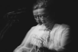 Photo en noir et blanc de Sarah Harmer jouant de la guitare. Deux images floues semblent juxtaposées l’une sur l’autre.