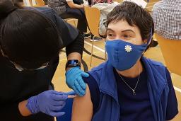 Une travailleuse de la santé se prépare à administrer un vaccin à un patient. Les deux personnes portent des masques médicaux.