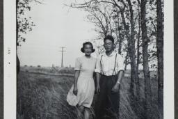 Un jeune couple canadien d’origine japonaise pose dans un champ avec des arbres en arrière-plan.