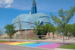 A rainbow crosswalk in front of the Canadian Museum for Human Rights on a sunny day