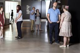 Des petits groupes de personnes en conversation debout dans un espace d’exposition de Musée.