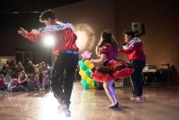 Trois danseurs habillés de rouge et de blanc se produisent devant une foule d'enfants au Musée canadien pour les droits de la personne.