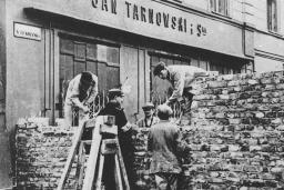 Groupe d’hommes en train d’ériger un mur de pierres dans une rue de la ville