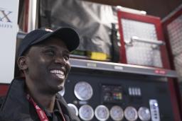 Un homme souriant devant un camion d’incendie.