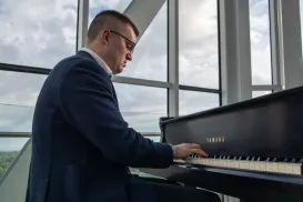 Un musicien vêtu d’un complet bleu foncé est assis et joue du piano.