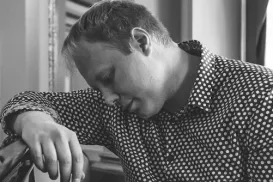 Un musicien est assis à un piano, l’index gauche sur une touche.