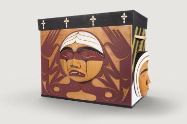 Une boîte de bois sculpté avec l'image d'un visage en souffrance.