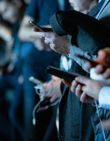Un groupe de personnes utilisant leurs téléphones portables debout. Visibilité masquée.