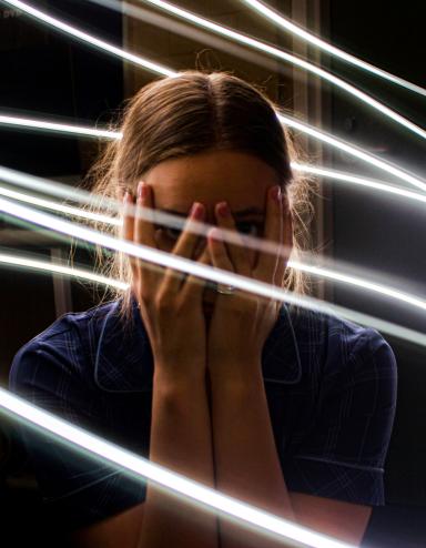 Une adolescente se couvre le visage de ses mains et regarde à travers ses doigts, l’air bouleversée. Des lignes lumineuses tourbillonnent autour d’elle. Visibilité masquée.