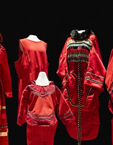 Cinq robes rouges de tailles et de modèles différents sont exposées sur des mannequins. Visibilité masquée.