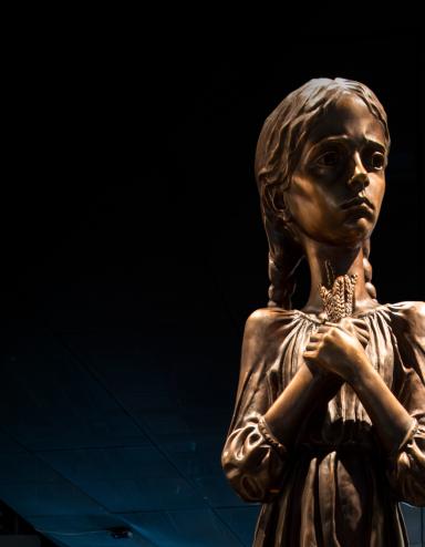 Une statue d’une fillette tenant des épis de blé. Visibilité masquée.