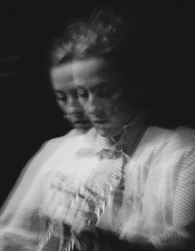 Photo en noir et blanc de Sarah Harmer jouant de la guitare. Deux images floues semblent juxtaposées l’une sur l’autre. Visibilité masquée.