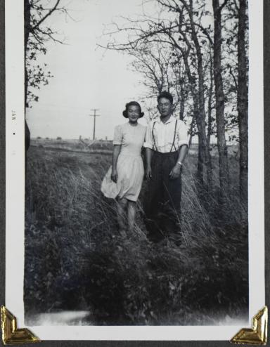 Un jeune couple canadien d’origine japonaise pose dans un champ avec des arbres en arrière-plan. Visibilité masquée.