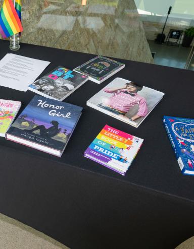 Une table avec une nappe noire et des livres colorés sur les 2SLGBTQI+. Visibilité masquée.