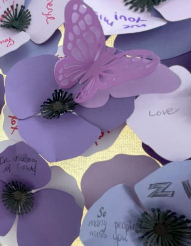 Des pavots violets faits de papier avec des noms et des messages écrits par des membres de la communauté ou de la famille de personne décédées après avoir consommé des drogues empoisonnées. Visibilité masquée.