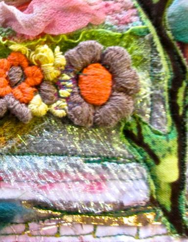 Une œuvre d’art textile colorée qui comprend des fleurs brodées, des branches et de la verdure mélangées à des couches de tissus roses, bleus et blancs. Visibilité masquée.