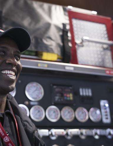 Un homme souriant devant un camion d’incendie.