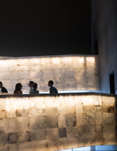 A group of people traveling up the Museum’s lighted alabaster ramps. Visibilité masquée.