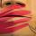 Un plan rapproché d’une boîte en bois, sur laquelle est sculpté un visage dont la bouche est recouverte d’une main peinte en rouge.