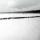 Une photo en noir et blanc d’un paysage plat et enneigé. On voit des arbres et des petits bâtiments au loin. Une longue file de plus de 100 personnes marchent dans la neige.