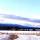 Une route de campagne couverte de neige; on voit des montages au loin.