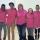 Six adolescents et adolescentes et une femme d'âge moyen, se tenant debout les bras les uns autour des autres, sourient vers l'objectif. Tous et toutes portent des t-shirts roses.