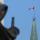 Un drapeau canadien flotte au sommet d’une grande tour. Au premier plan se dresse la statue d’une femme voilée portant une épée.
