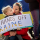 Un enfant tient un panneau de protestation qui dit, en anglais : « Poutine, ne touche pas à l’Ukraine. » L’enfant est assis sur les genoux de la personne qui s'occupe de lui. Derrière eux se trouve un drapeau ukrainien.