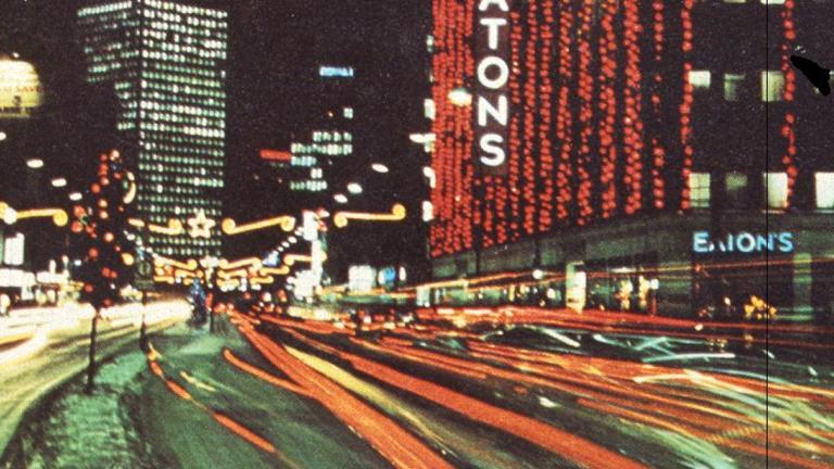 Photo du centre-ville de Winnipeg à la fin des années 1960 où l’on voit l’édifice Eatons décoré de nombreuses lumières de Noël. Visibilité masquée.