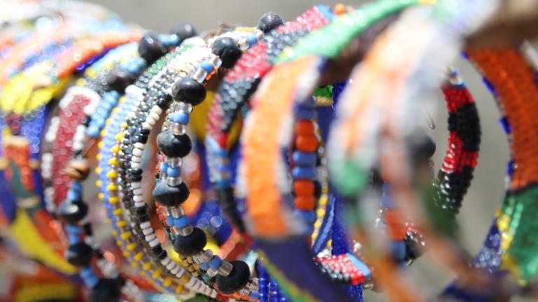Un étalage de bracelets en perles colorés est présenté à la vente. Visibilité masquée.