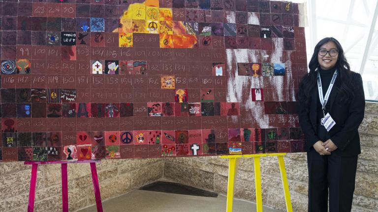 Deux élèves debout de chaque côté d’une grande œuvre d’art exposée sur deux chevalets. Visibilité masquée.