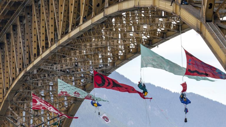 Plusieurs grandes bannières triangulaires sont suspendues au bas d’un grand pont.