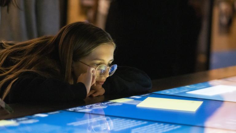 A girl looks at a horizontal interactive display with interest. Visibilité masquée.