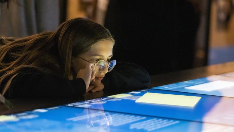 A girl looks at a horizontal interactive display with interest. Visibilité masquée.