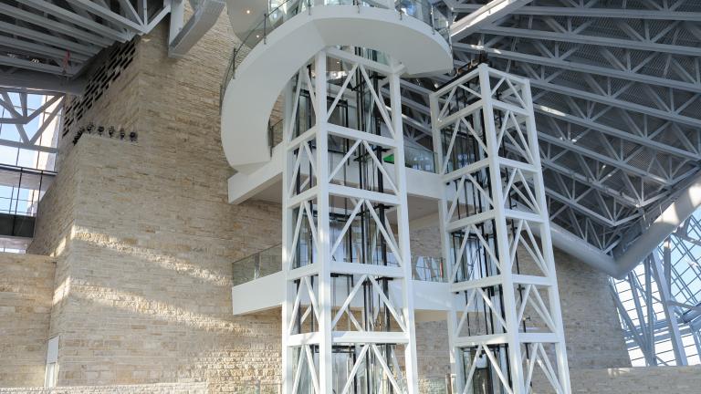 L’intérieur d’un grand espace ouvert du Musée avec deux cages d’ascenseur au centre de l’image, ainsi qu’un mur de calcaire.