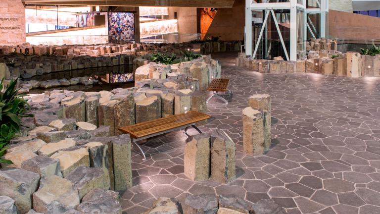 Des piliers de pierre d'environ un à deux pieds de haut sont regroupés et font saillie sur le sol. Deux bancs en bois se trouvent au centre de l'image.