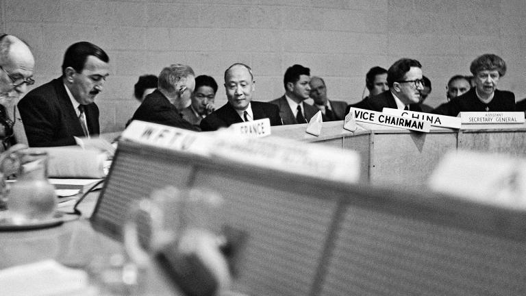 Photo d'archives en noir et blanc d'un groupe de personnes assises autour d'une table de conférence.