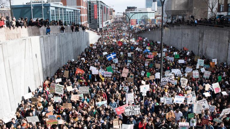 Des milliers de personnes tiennent des pancartes et des bannières de protestation et défilent dans la rue.