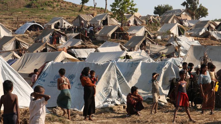 Camp densément recouvert de tentes de toile, à flanc de colline. On y voit de nombreux réfugiés tant à l’intérieur qu’à l’extérieur des tentes.